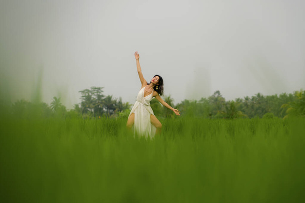 mente e corpo conexão com a natureza - meia-idade atraente e feliz mulher japonesa asiática em vestido de verão desfrutando de destino tropical idílico dançando livre
 - Foto, Imagem