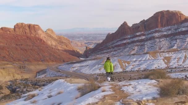 DRONE: Vrouwelijke reiziger wandelingen langs pad met uitzicht op de snelweg over de canyon - Video