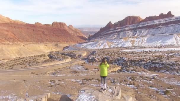 AERIAL, VERTIGO: Vrouw maakt foto 's van de oversteek van de winterse canyon. - Video