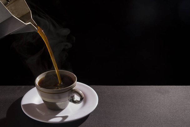 podawanie lub nalewanie gorącej kawy do filiżanki w czarnym tle - Zdjęcie, obraz