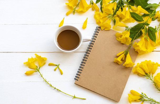 notebook planejador para o trabalho de negócios com café quente, arranjo de flores amarelas flat lay estilo no fundo branco de madeira
 - Foto, Imagem