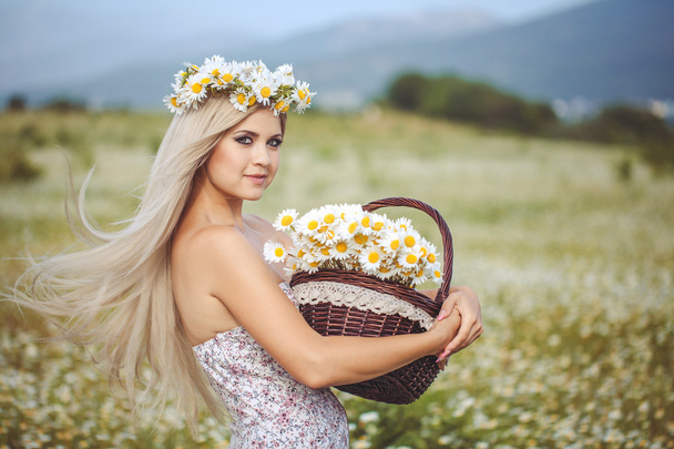 Attractive blonde in chamomile field. Young woman in wreath - Fotografie, Obrázek