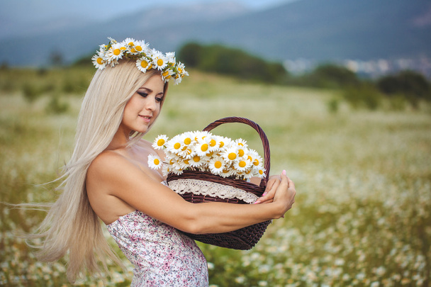 Attractive blonde in chamomile field. Young woman in wreath - 写真・画像
