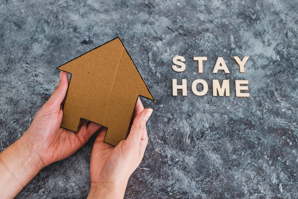 társadalmi távolság ellen covid-19 vírus, Stay Home üzenet kézben tartott ház ikon mellett szöveg - Fotó, kép