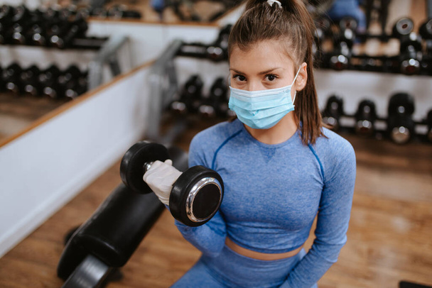 jeune belle femme caucasienne dans des masques de protection dans la salle de gym avec des poids
 - Photo, image