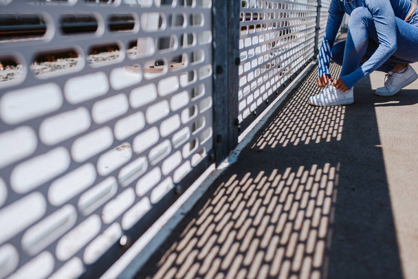  tyttö sininen urheiluvälineet sitominen kengännauhat sillalla.  - Valokuva, kuva