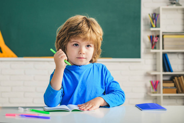 Little child at school lesson. Kids gets ready for school. School education and people concept - cute pupil over blackboard background. - Φωτογραφία, εικόνα