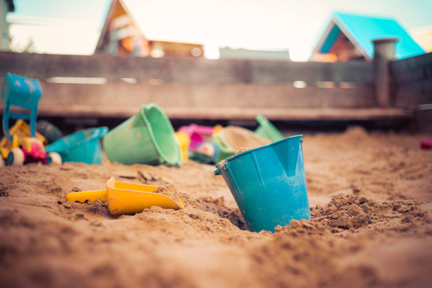 Children plastic toys in the sand box. Dirt bucket, selective focus.  - Fotó, kép