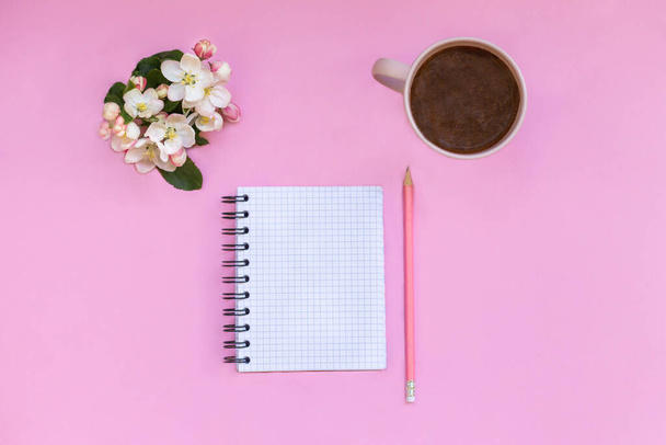 ノートのノートはピンクの背景にあり、ペン、コーヒー、花の隣にあります。個人的な時間と作品の企画    - 写真・画像