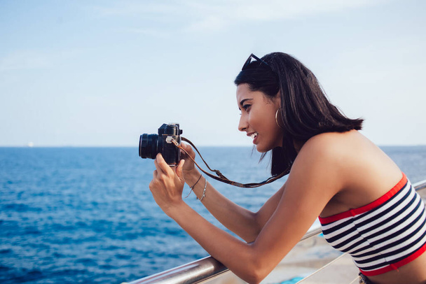 Young Hispanic tourist concentrated on lens focus for photographing horizon skyline of majestic seashore, skilled professional journalist taking pictures during travel vacations near ocean - Photo, Image
