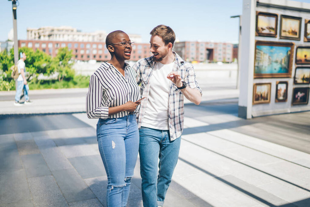 Cheerful young multiracial friends in casual clothes having fun and interesting conversation while enjoying pastime and walking together in urban streets - Foto, Bild