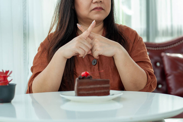Las mujeres gordas se niegan a comer pasteles de chocolate. Intención de perder peso para una buena salud y buena forma - Foto, Imagen
