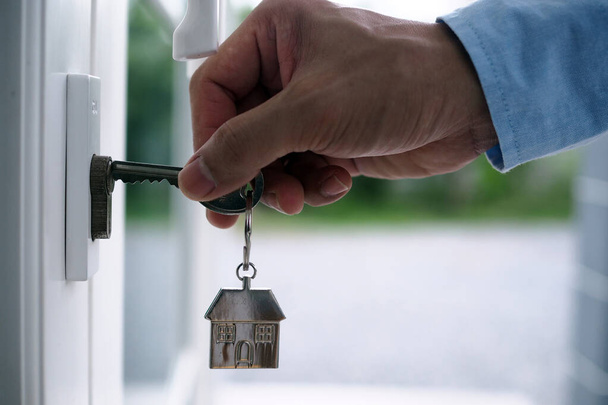 Рука банкира держит ключ от дома. Концепция ипотеки дома и земли - Фото, изображение