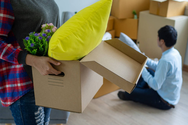 The wife is carrying the box for personal items and the husband is packing the box. Couples prepare to move to a new home. - Photo, Image