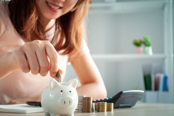 Happy Asian women put money in a piggy bank. save money concept - Photo, Image