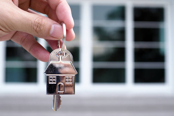 Bankacının eli evin anahtarını tutar. Ev ve arazi ipoteği kavramı - Fotoğraf, Görsel