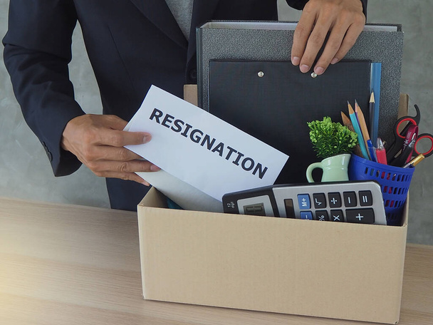 Geschäftsleute verstauen persönliche Gegenstände in einer braunen Pappschachtel. Und ein Rücktrittsschreiben - Foto, Bild