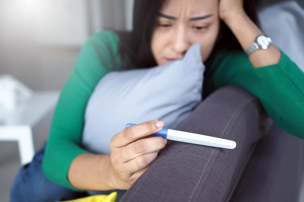 У азиатских женщин тревожное выражение лица и они думают о непреднамеренных результатах теста на беременность. - Фото, изображение