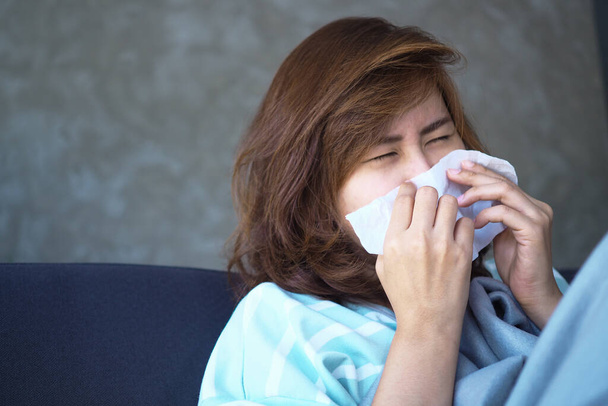 La mujer está enferma de dolor de cabeza, fiebre alta y gripe, sentada debajo de una manta - Foto, Imagen