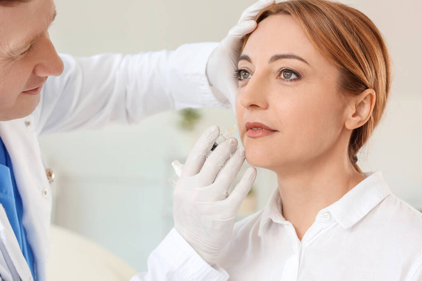 Woman receiving filler injection in beauty salon - Foto, afbeelding