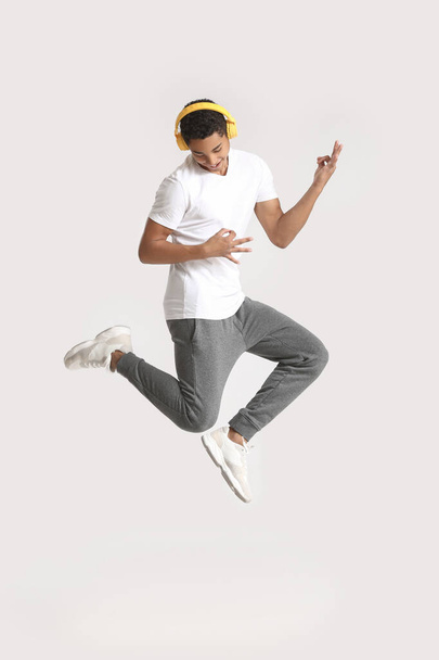 Adolescente afro-americano che balla e ascolta musica su sfondo chiaro
 - Foto, immagini