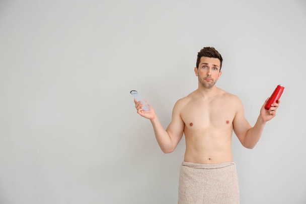 Jóképű férfi zuhanyzóval zselék könnyű háttér - Fotó, kép