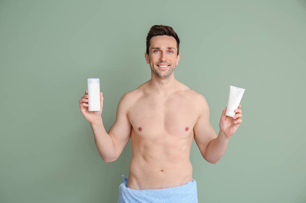Handsome man with shower gels on color background - Photo, Image