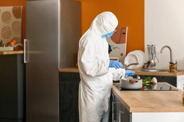 Woman in biohazard suit cooking in kitchen - Φωτογραφία, εικόνα