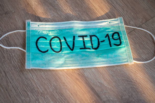 Маска написать Covid-19 с естественным освещением. Ситуация с вирусной инфекцией 2019-nCoV распространяется по всему миру. Смертельная чума мира. Концепция носить маску для защиты коронавируса - Фото, изображение