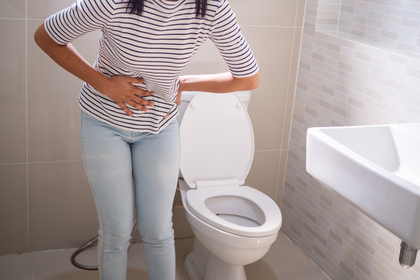 Mujer con diarrea de pie en el baño, sosteniendo su estómago. Dolor de estómago severo, prepárate para sentarte estiércol en el baño - Foto, Imagen