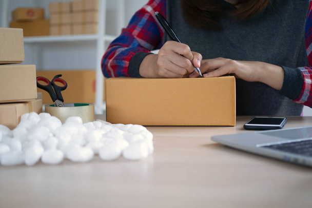 women checking address and write on box before sent to customers.Women use pen write on box and use foam protect impact during transportation/ - Photo, Image