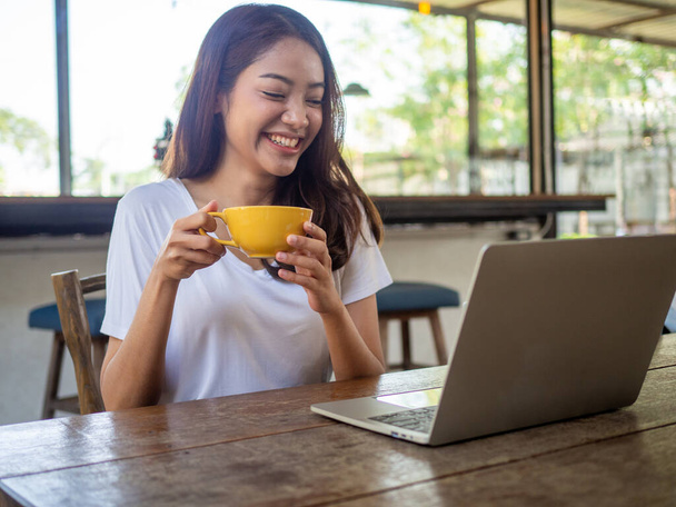 Le donne asiatiche di età compresa tra 20 e 30 anni sono felici di comunicare con gli amici stranieri tramite computer nella caffetteria.. - Foto, immagini