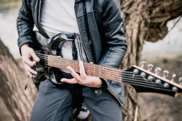 Technique of playing the electric guitar - a man playing outdoors - heavy hard rock and blues music - 写真・画像