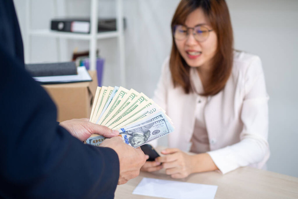 General manager presenting an envelope with premium or bonus cash to female official. Boss congratulating happy employee with career promotion, thanking for good job and giving financial reward - Photo, Image