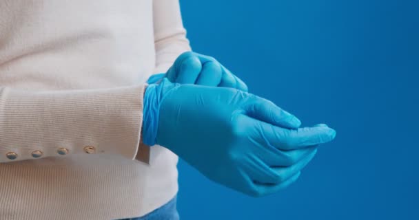 Woman taking off blue medical rubber gloves - Filmati, video