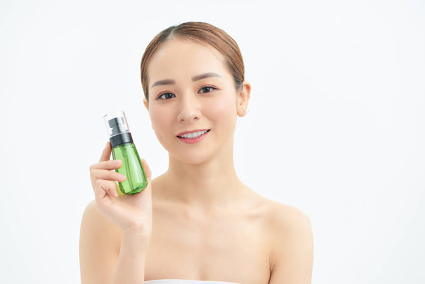 glücklich junge schöne Frau zeigt kosmetische Flasche über weißem Hintergrund. - Foto, Bild