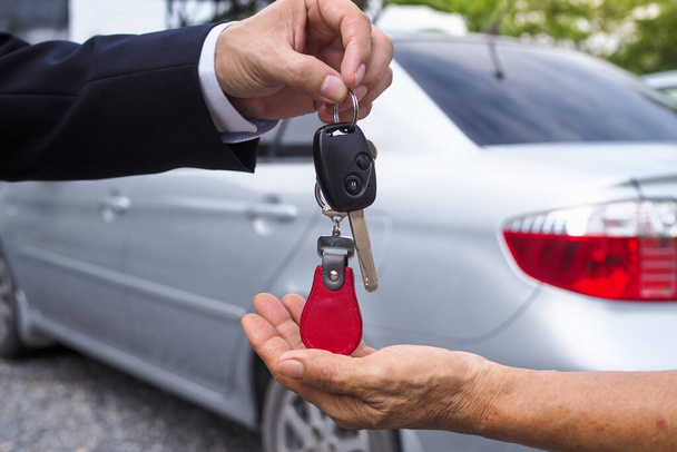 The car salesman and the key to the new owner. - Foto, afbeelding