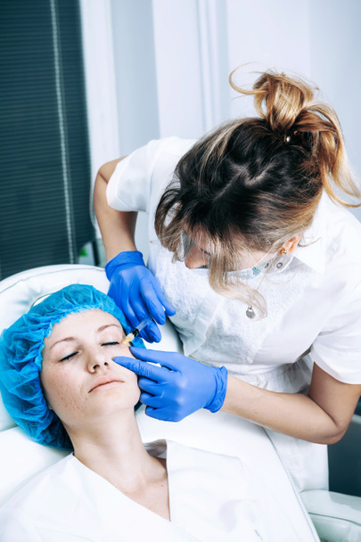 Arzt Kosmetologe macht Rejuvenating Biorevitalization Gesichtsinjektionen Verfahren auf der weiblichen Haut in Schönheitssalon - Foto, Bild