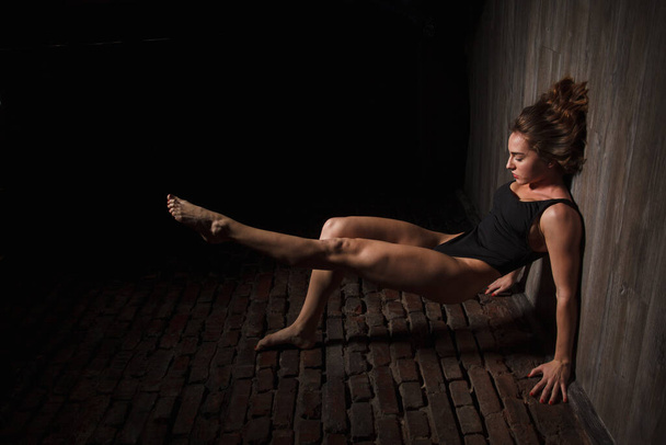 Girl in black swimsuit does yoga against the background of a brick wall - Φωτογραφία, εικόνα
