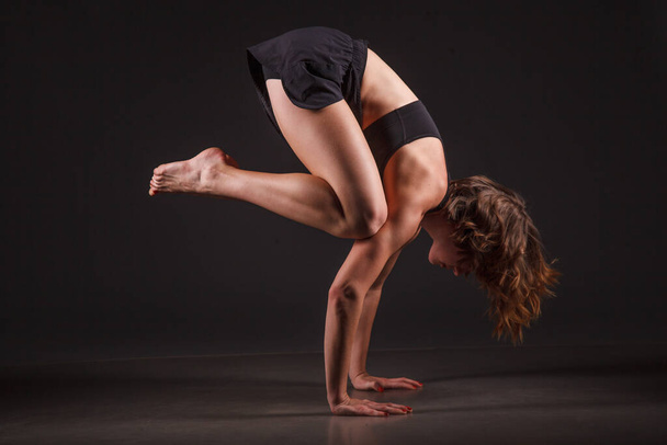 Young girl doing yoga on a black background - Foto, Bild