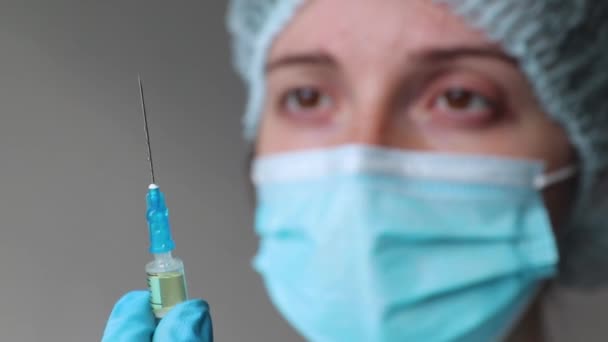 doctor holds a syringe and looks at it in the background of his face  - Πλάνα, βίντεο