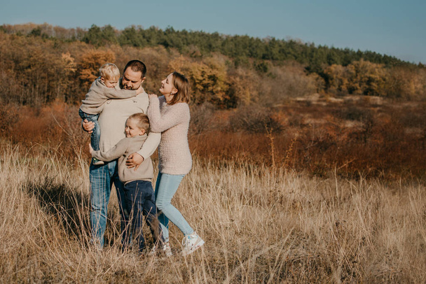 Global Day of Parents. Happy family enjoying together on a sunny day in country. father, mother and two boy children having fun and playing in nature - Фото, изображение