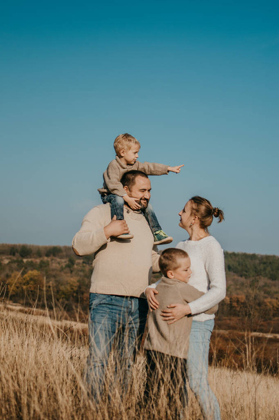 Global Day of Parents. Happy family enjoying together on a sunny day in country. father, mother and two boy children having fun and playing in nature - Fotoğraf, Görsel