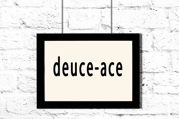 Marco negro colgado en la pared de ladrillo blanco con inscripción deuce-ace
 - Foto, Imagen