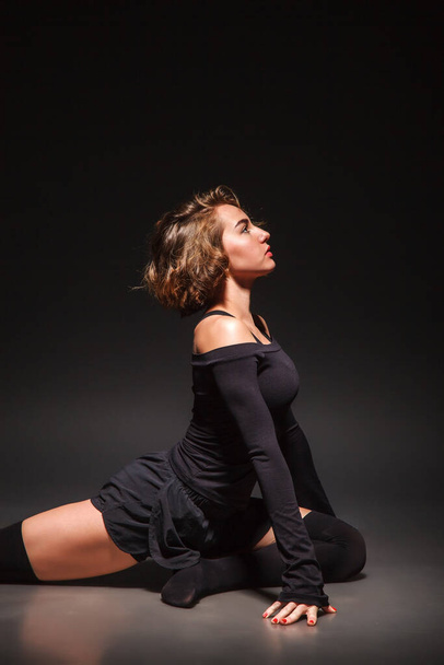 Young girl doing yoga on a black background - Φωτογραφία, εικόνα