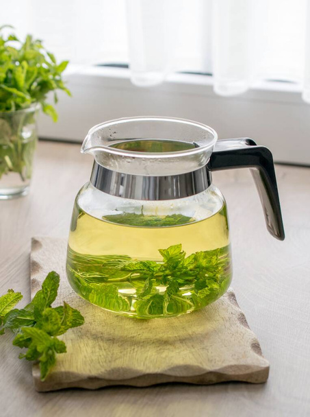 Свіжозварений скляний горщик трав'яного м'ятного чаю на кухонному столі
 - Фото, зображення