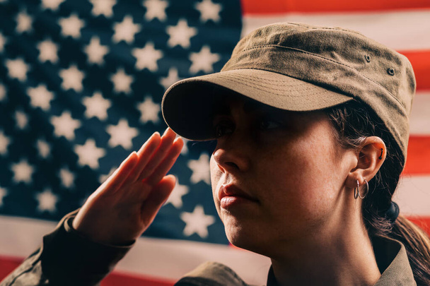 Giorno della memoria. Un ritratto ravvicinato di soldato donna in uniforme saluta sullo sfondo della bandiera americana. Il concetto delle festività nazionali americane e del patriottismo
. - Foto, immagini