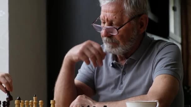Little boy child play chess with his grandfather, senior positive man - Footage, Video