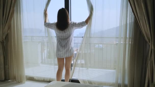 Zurück Ansicht der Frau öffnen Vorhänge am Fenster und genießen einen neuen Tag zu Hause, Blick durch das Fenster genießen Licht Stadt Morgen und träumen in der Wohnung - Filmmaterial, Video