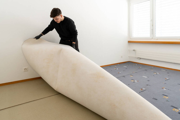 ammatillinen siivooja laitoshallintayhtiöstä poistaa ruma vanha matto makuuhuoneessa puhdistus- ja kunnostustöiden aikana
 - Valokuva, kuva